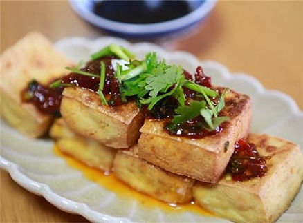 tofu blocks stacked together with a sauce and cilantro