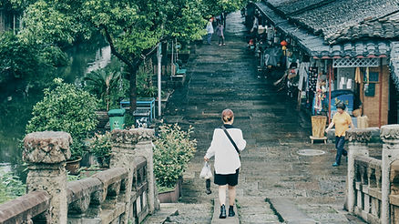 woman walking over bridge through old chinese neighborhood