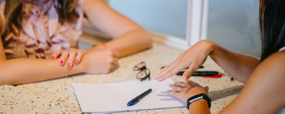Two women sitting at a table and discussing a paper